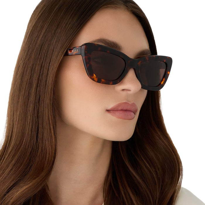 on model - female wearing diff eyewear featuring the adriana cateye sunglasses with a rich tortoise acetate frame and brown lenses angled view