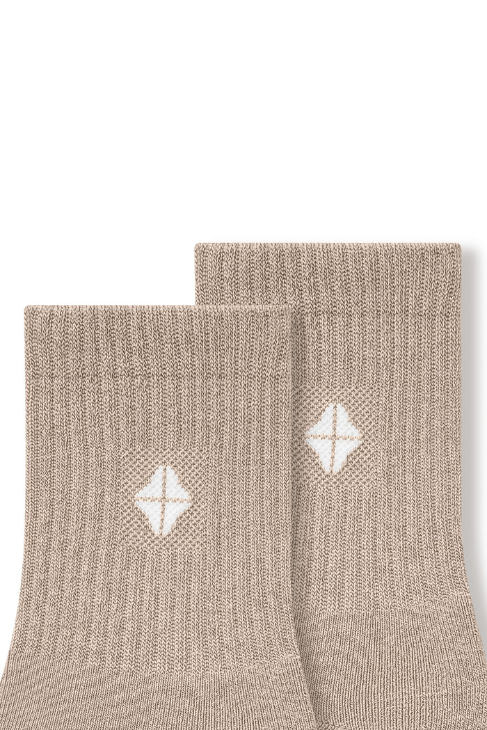 Top part of Adult Crew Socks in Bisque with Kyte Baby logo on a white background
