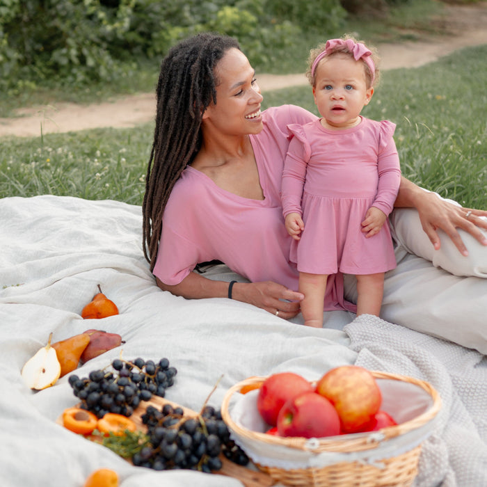 Woman wearing Kyte Baby Women's V-Neck in Apple Blossom next to baby wearing matching Twirl Bodysuit Dress
