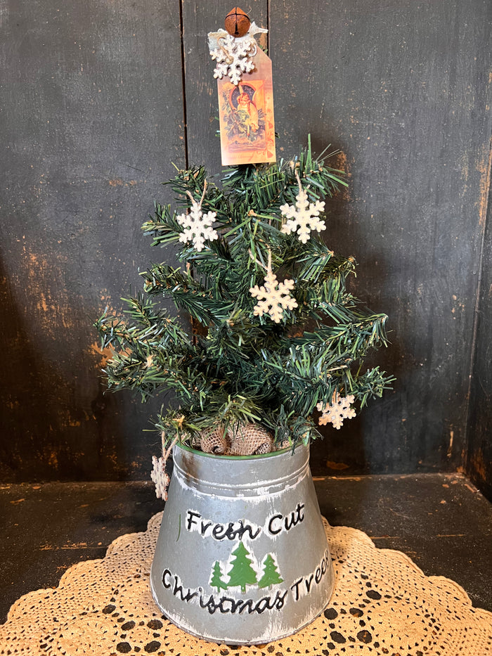 Tree In Fresh Cut Tree Bucket w/ Tag, Bell And Snowflake Topper