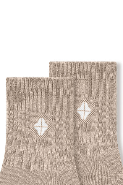 Top part of Adult Crew Socks in Bisque with Kyte Baby logo on a white background