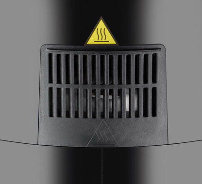 Nahaufnahme einer schwarzen Entlüftungsöffnung mit vertikalen Lamellen an der Unold Heißluftfritteuse XL. Darüber befindet sich ein dreieckiges Warnschild mit Hitzewellensymbol, das auf heiße Luft oder eine Wärmequelle hinter der Entlüftung hinweist.
