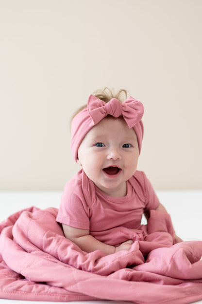 Infant wearing Apple Blossom Bodysuit and Bow wrapped in matching Baby Blanket in Apple Blossom TOG 1.0