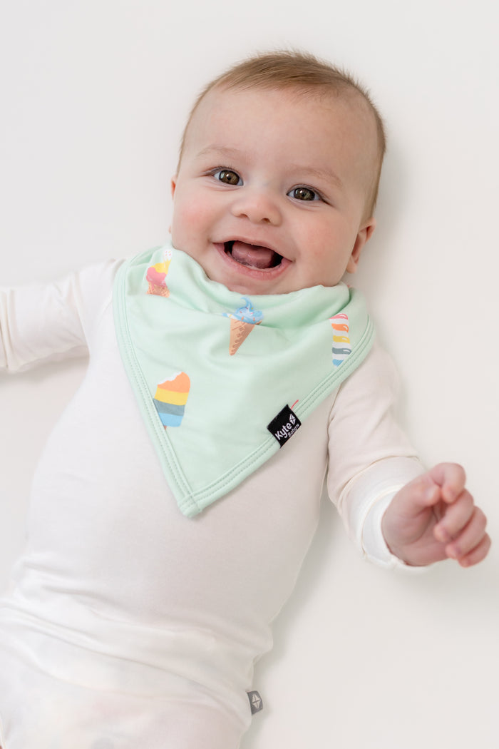 Baby smiling in Mint Ice cream print Bib over a white bodysuit on a white background