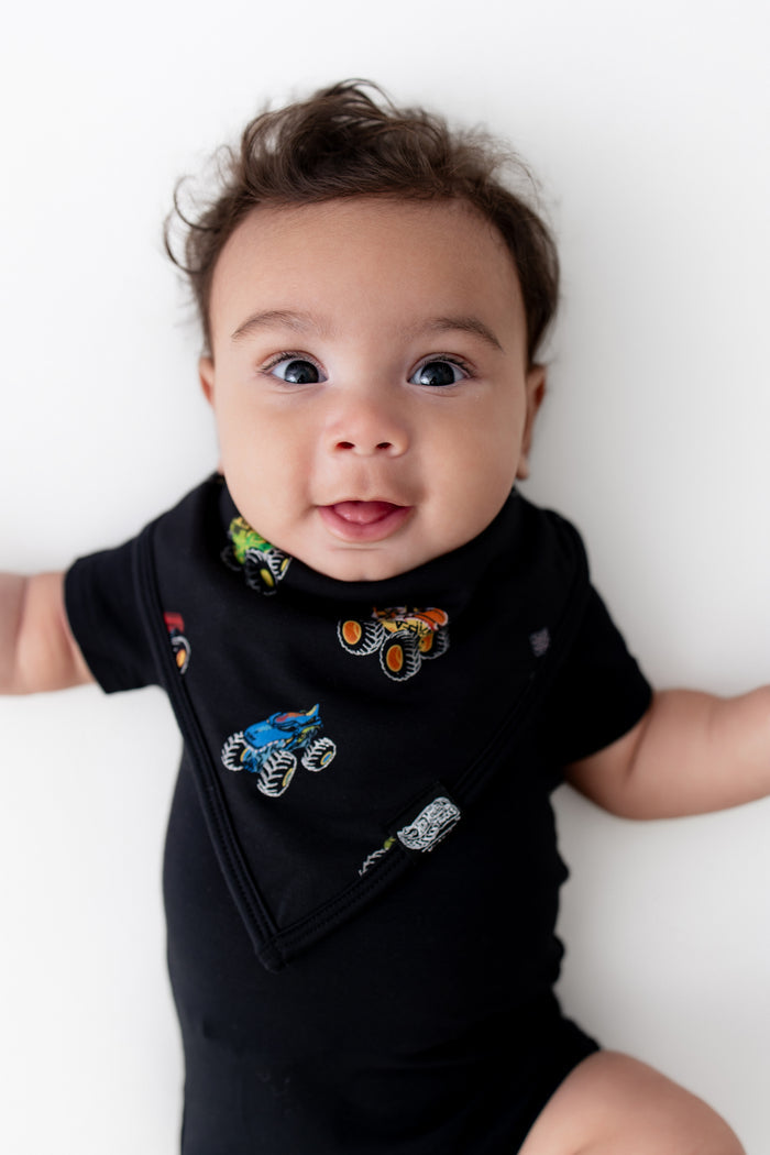 Baby in black Bib in Monster Truck print over a black bodysuit on white background