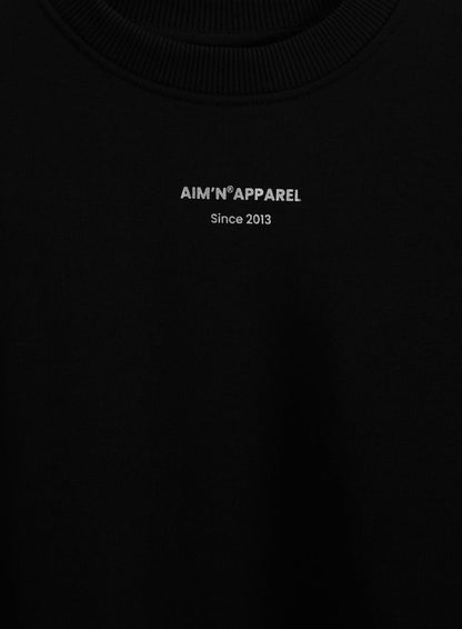 Silver aim'n logo print on a black terry sweatshirt with a ribbed round neckline.