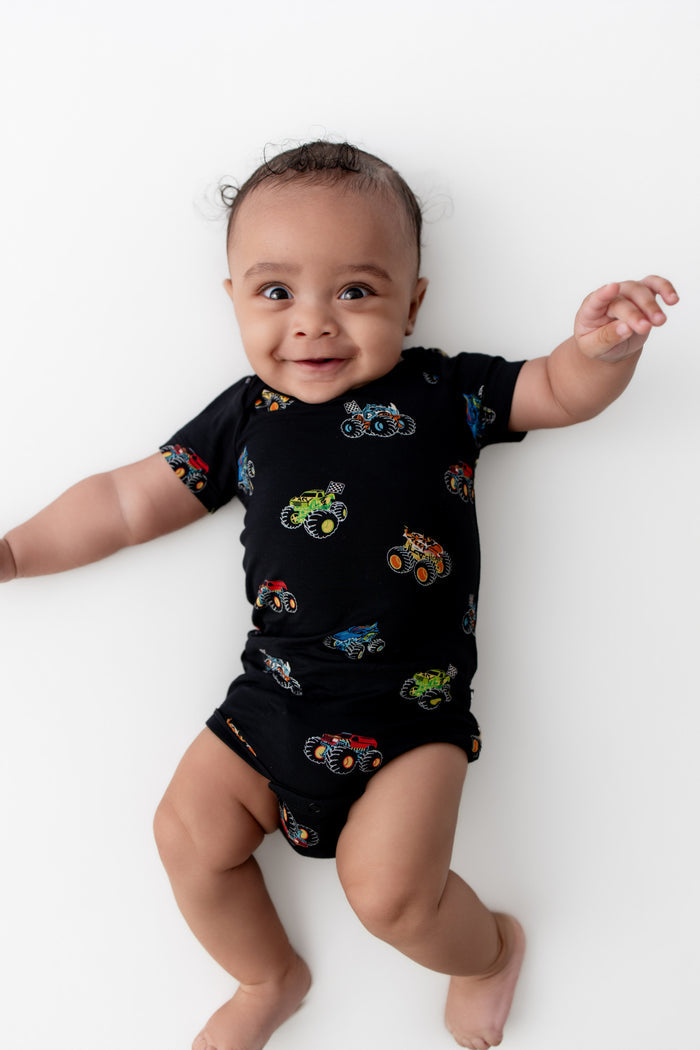 Baby wearing Black Bodysuit in Monster Truck print on white background