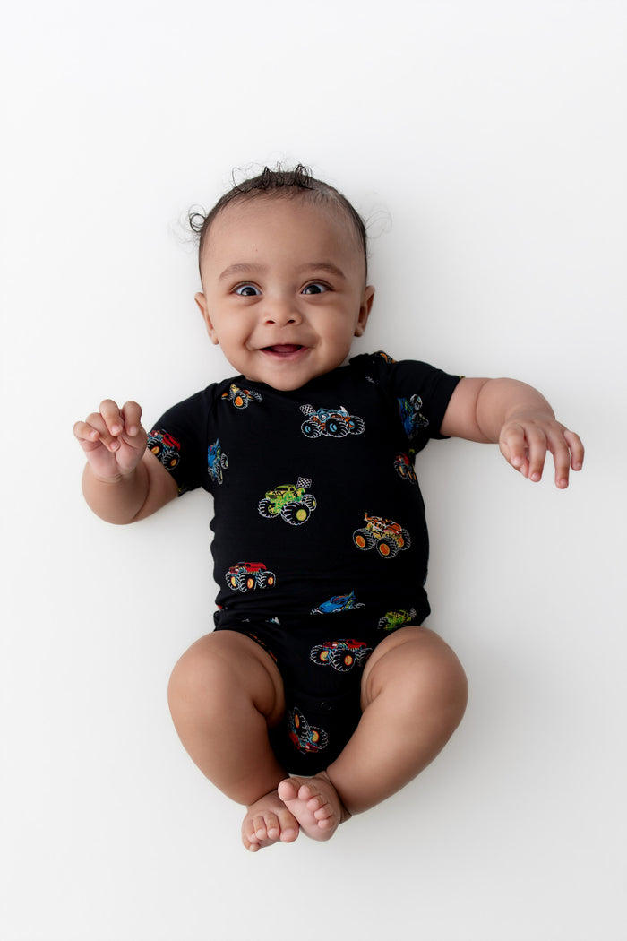 Baby smiling in Black Bodysuit in Monster Truck print on white background