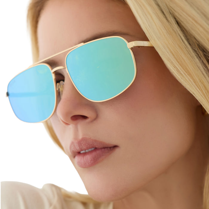 on model - blonde female wearing diff eyewear charley navigator sunglasses with a gold metal frame and dew drop blue mirrored lenses detailed view
