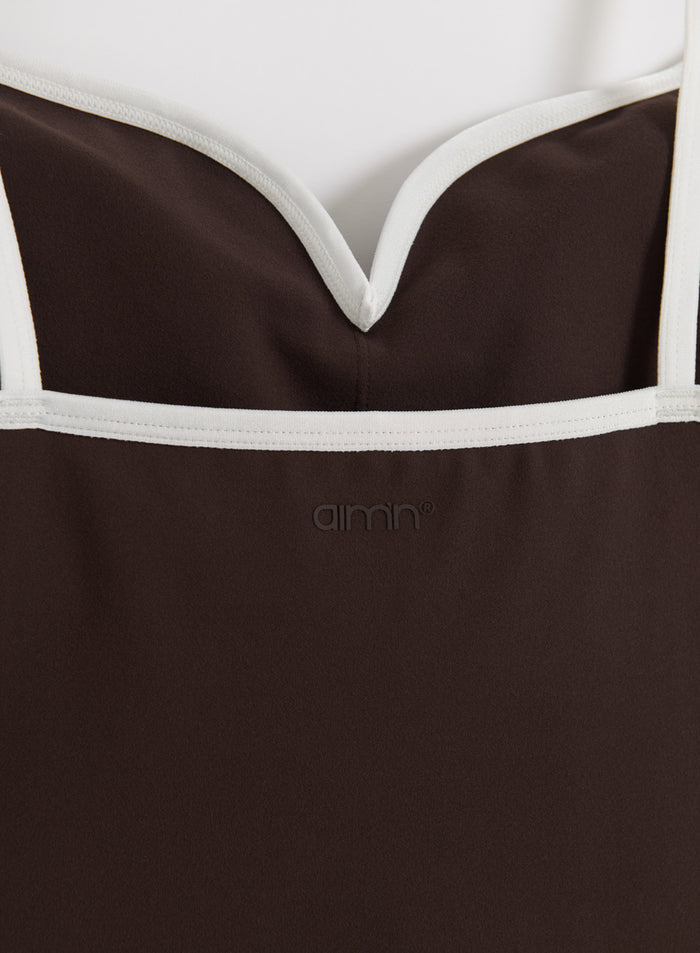 Detailed close-up of the chocolate Sense Contour Singlet featuring white contrast trim and the aim'n logo.