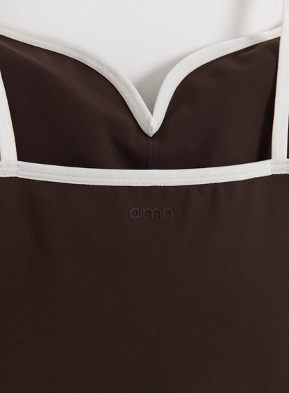 Detailed close-up of the chocolate Sense Contour Singlet featuring white contrast trim and the aim'n logo.