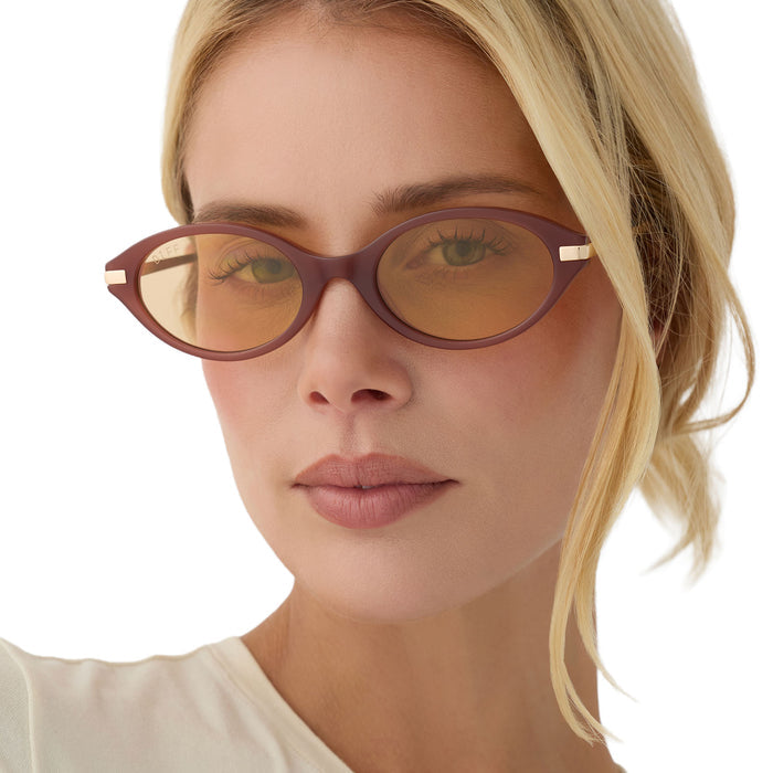 on model - blonde female wearing diff eyewear claudine oval sunglasses with a terracotta brown acetate frame, gold metal temples and champagne yellow tint lenses front view