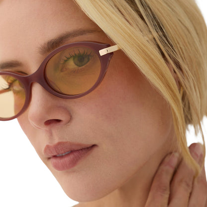 on model - blonde female wearing diff eyewear claudine oval sunglasses with a terracotta brown acetate frame, gold metal temples and champagne yellow tint lenses detailed view