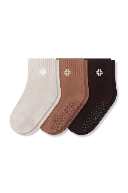Three pairs of grip socks in cream, tan, and dark brown, arranged side-by-side on a plain white background.