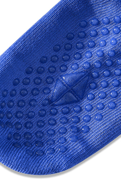 A close-up of a blue textured grip sock with raised circular dots and a central triangular tread, shown on a white background.