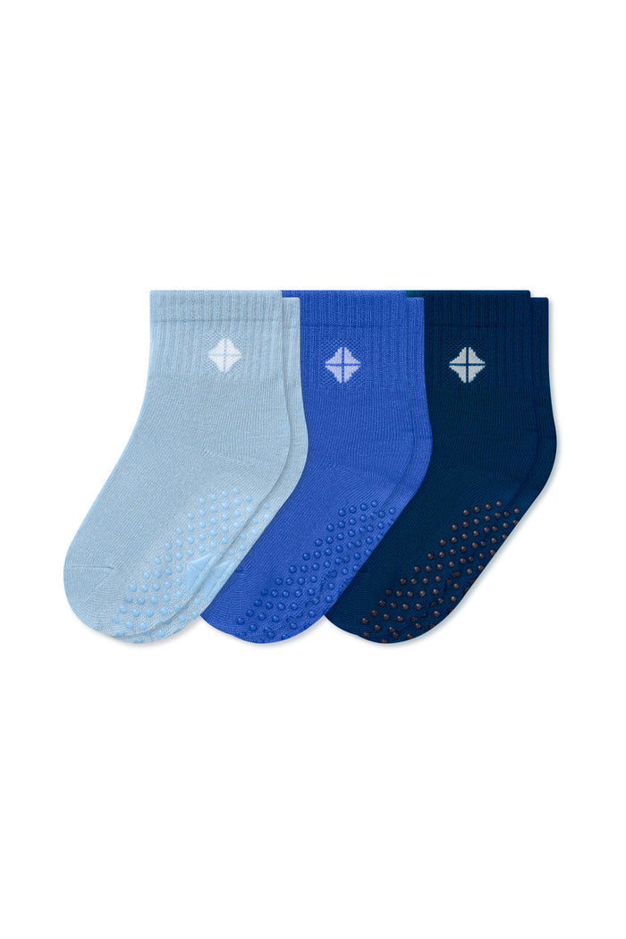 Three pairs of ankle socks in light blue, royal blue, and navy blue, arranged in a fan shape on a plain white background. Each sock features a textured grip pattern on the sole and a small white geometric logo on the cuff.