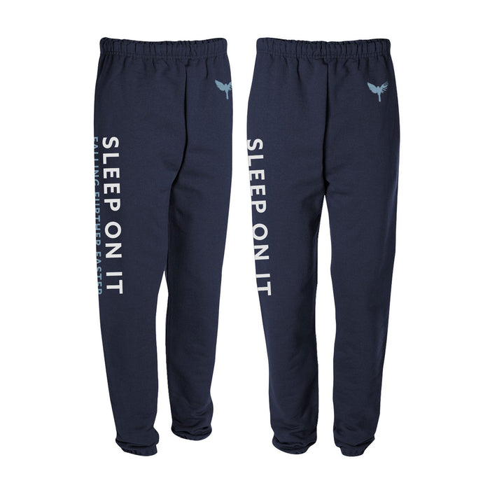 Navy blue Sleep On It sweatpants with elastic waist and cuffs, featuring “SLEEP ON IT” printed in white on the left leg, a winged heart graphic, and an embroidered logo near the left pocket.