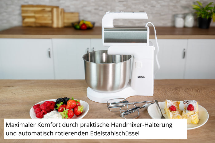 Der Unold Handmixer Hannah mit Rührschüssel, ein weißer Standmixer mit Edelstahlschüssel, steht auf der Küchentheke neben Tellern mit Beeren und Kuchen. Der deutsche Text hebt seinen Komfort, den praktischen Handmixerhalter und die automatisch rotierende Schüssel hervor.