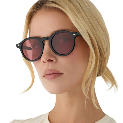 on model - blonde female wearing diff eyewear x harry potter birthday round sunglasses with a black acetate frame and dusk pink lenses angled view