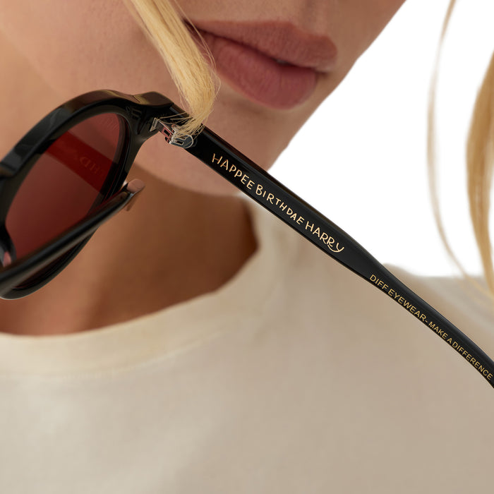 on model - blonde female holding diff eyewear x harry potter birthday round sunglasses show casing the inside of the temple with messaging "happee bithdae harry"