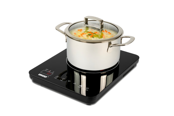 Ein Edelstahltopf mit Glasdeckel, gefüllt mit Gemüsesuppe, steht auf der Unold Induktionskochplatte Ina - einem schwarzen Induktionskochfeld mit digitaler Steuerung.