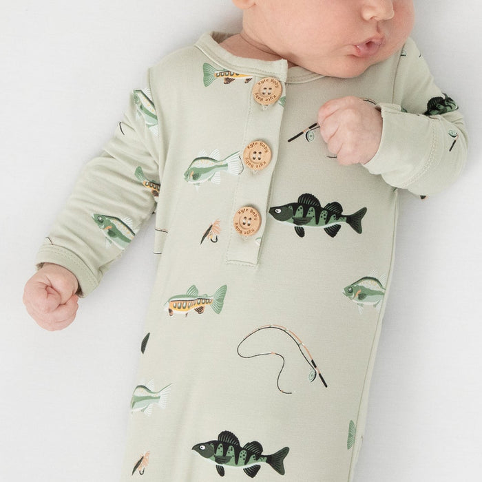 newborn laying on a white blanket wearing the Knotted Gown with Hat Set in Fishing tied at the bottom