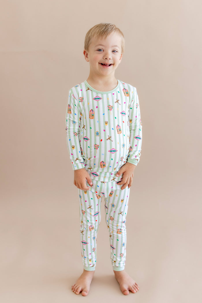 Child wearing a green and white striped long sleeve pajama set with colorful Harry Potter patterns on a beige background