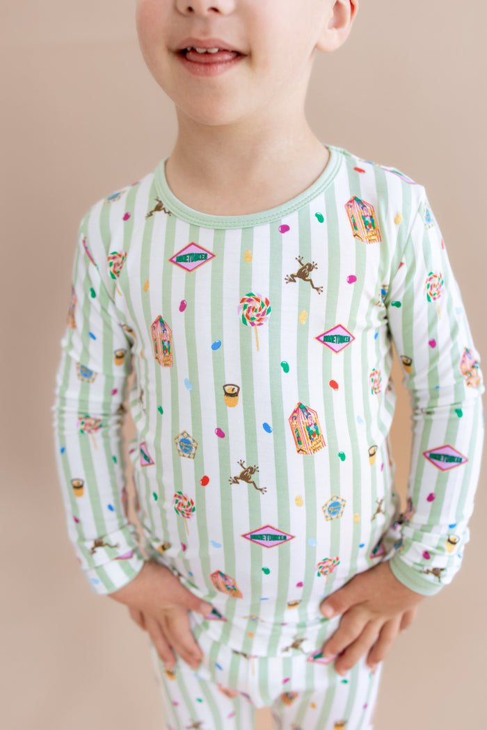 Child wearing a green and white striped long sleeve pajama set with colorful Harry Potter patterns on a beige background