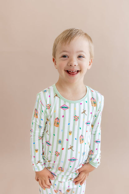 Child wearing a green and white striped long sleeve pajama set with colorful Harry Potter patterns on a beige background