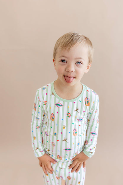 Child wearing a green and white striped long sleeve pajama set with colorful Harry Potter patterns on a beige background