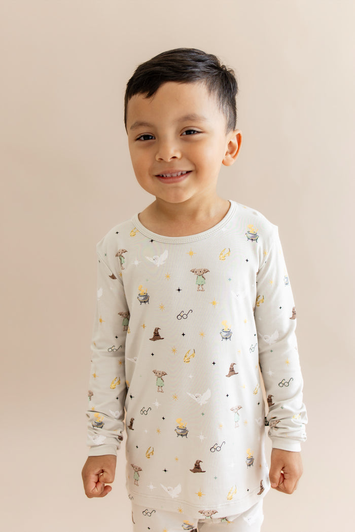 Child wearing a long-sleeve pajama shirt with Harry Potter prints on a beige background