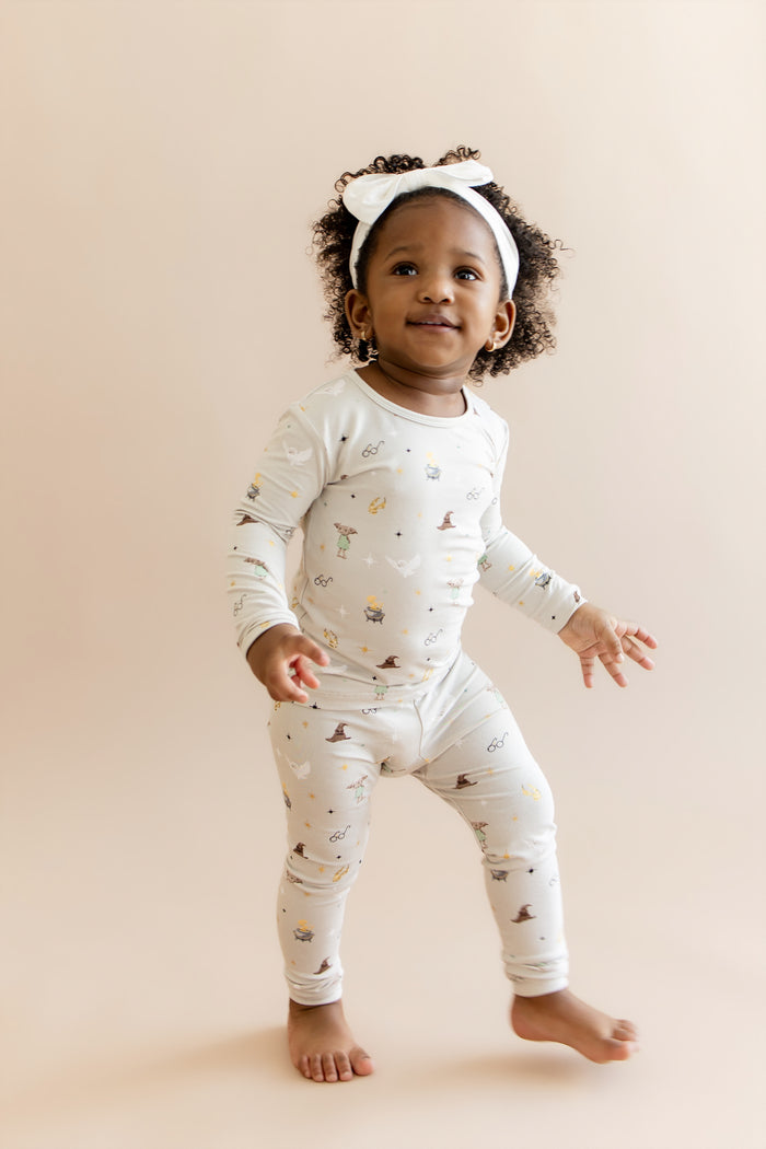 Child wearing a cream pajama set with Harry Potter prints on a beige background