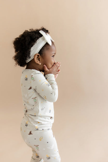 Child wearing a Harry Potter patterned pajama set with a white headband on a beige background
