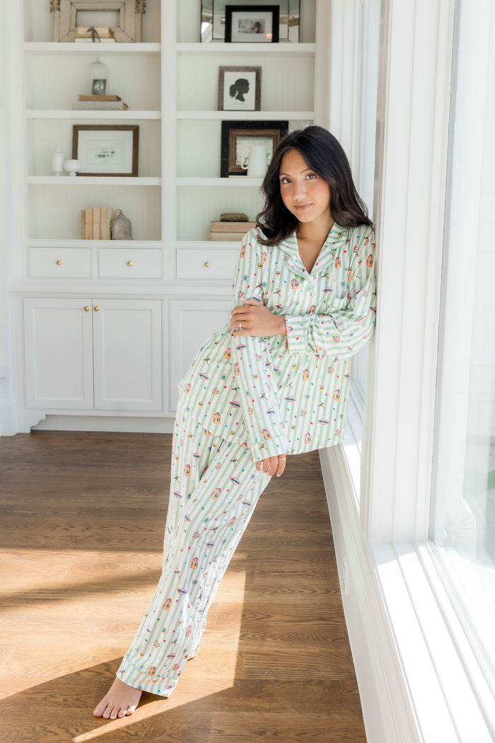 Model standing against a window in a room wearing a green and white striped Long-Sleeved Women's Pajama Set with colorful Harry Potter patterns on it.