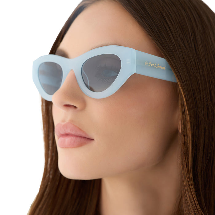 on model - female wearing for love & lemons diff eyewear featuring the lucy cat eye sunglasses with a pastel blue acetate frame and blue gradient polarized lenses angled view