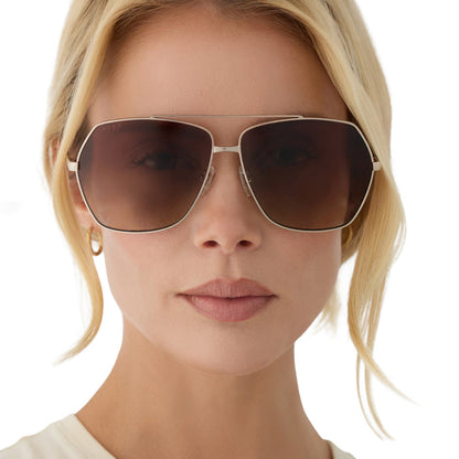 on model - blonde female wearing diff eyewear maude oversized aviator sunglasses with a gold metal frame and brown gradient polarized lenses front view