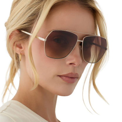 on model - blonde female wearing diff eyewear maude oversized aviator sunglasses with a gold metal frame and brown gradient polarized lenses angled view