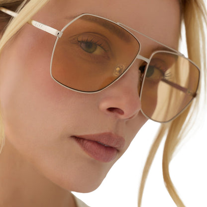 on model - blonde female wearing diff eyewear maude oversized aviator sunglasses with a gold metal frame and champagne yellow tint lenses angled view