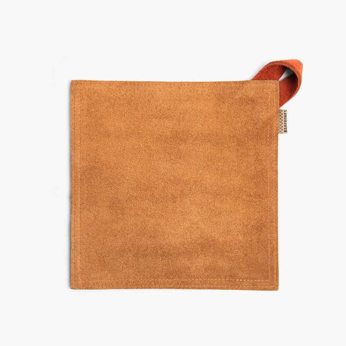 Tan suede leather hot pad with a Terracotta hanging strap on a white background
