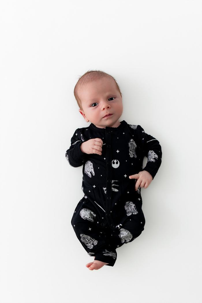 Infant laying on a white surface wearing the Romper in STAR WARS™