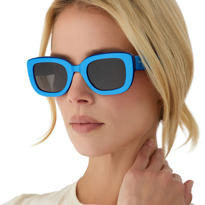 on model - blonde female wearing diff eyewear romy square sunglasses with a luminous blue acetate frame and grey lenses angled view