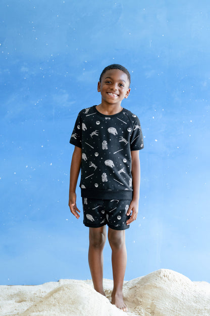 Young boy modeling the Short Sleeve Jogger Set in STAR WARS™ standing in sand  and a blue sky backdrop