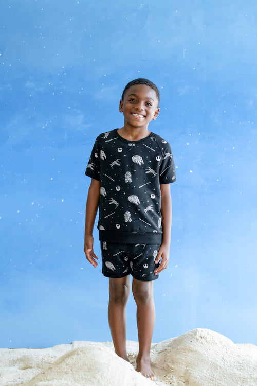 Young boy modeling the Short Sleeve Jogger Set in STAR WARS™ standing in sand  and a blue sky backdrop