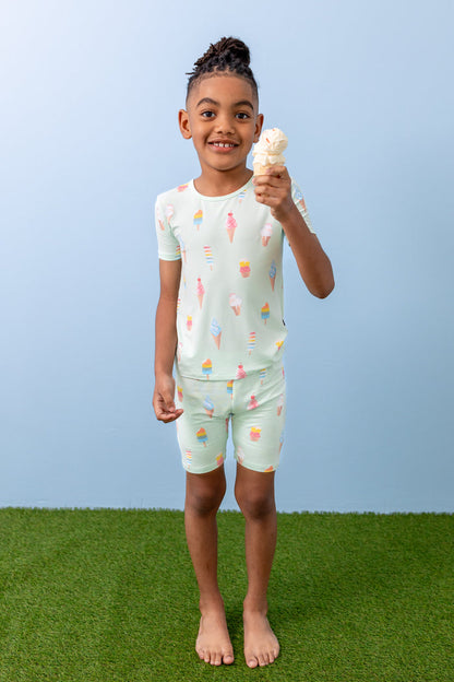 Child holding an ice cream cone wearing Mint Ice Cream print short sleeve pajama set on green grass