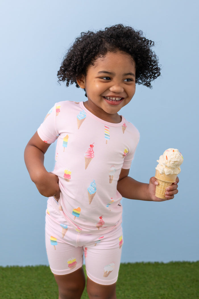 Child holding an ice cream cone wearing Sakura Ice Cream print short sleeve pajama set on green grass