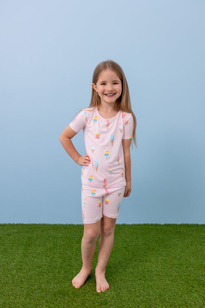 Child standing in Sakura Ice Cream print short sleeve pajama set on blue background and green grass