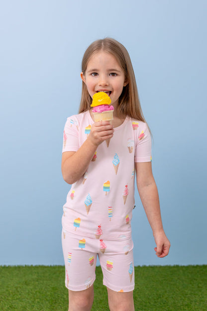 Child eating ice cream cone wearing Sakura Ice Cream print short sleeve pajama set on blue background and green grass