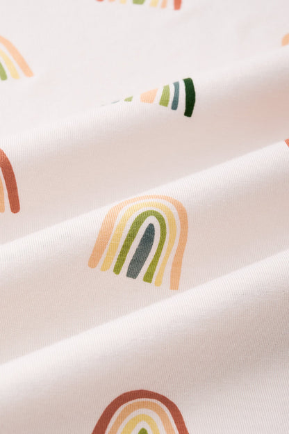 An all-over print featuring alternating rows of boho style rainbows in alternating directions over a light beige background color called Vanilla. 

One row of rainbows has an outermost arc colored in a dark cool green, followed by a cool sage green, then a light olive green, and finished with an inner core colored in a light apricot. 

Another row of of rainbows has an outermost arc colored in a burnt orange called Apricot, followed by a light peach, then a light yellow called Lilikoi, and finis