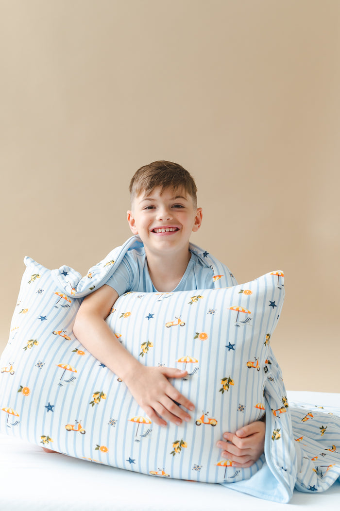 Young boy sitting on the bed holding a Standard Pillowcase in Amalfi Coast