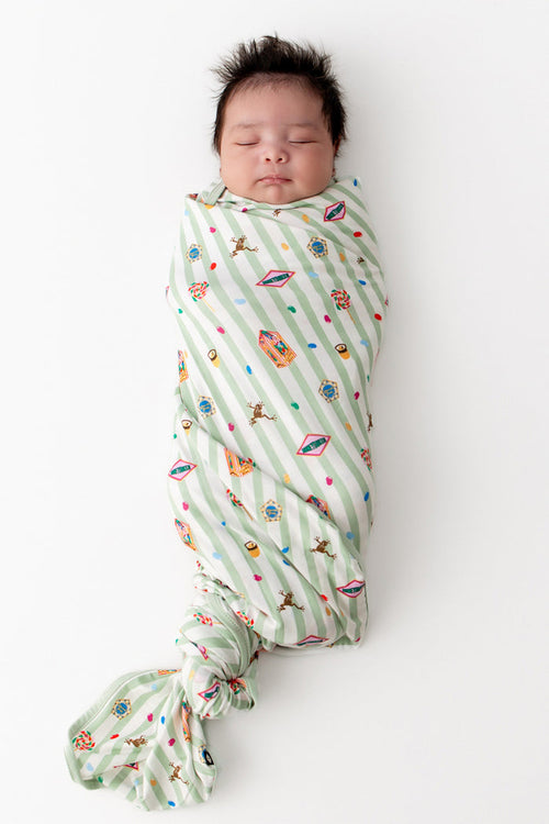 Baby wrapped in a green and white striped Swaddle blanket with colorful Harry Potter patterns on a white background